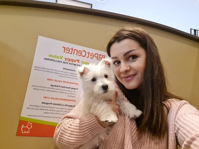 A woman holding a white puppy