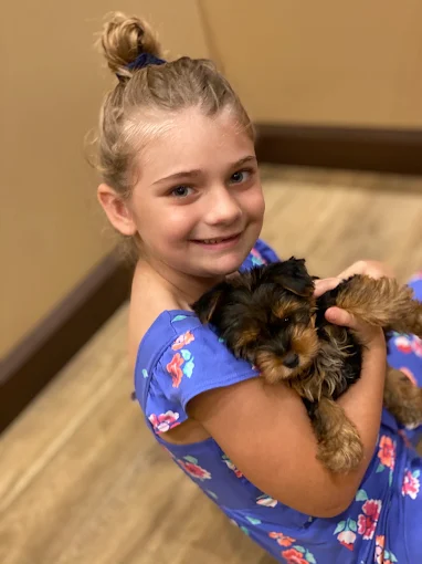 A girl holding a small puppy